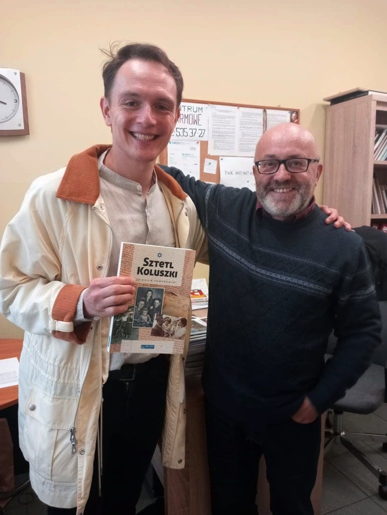 Jason standing next to Zbigniew Komorowski in Koluszki holding the book Shtetl Koluszki.