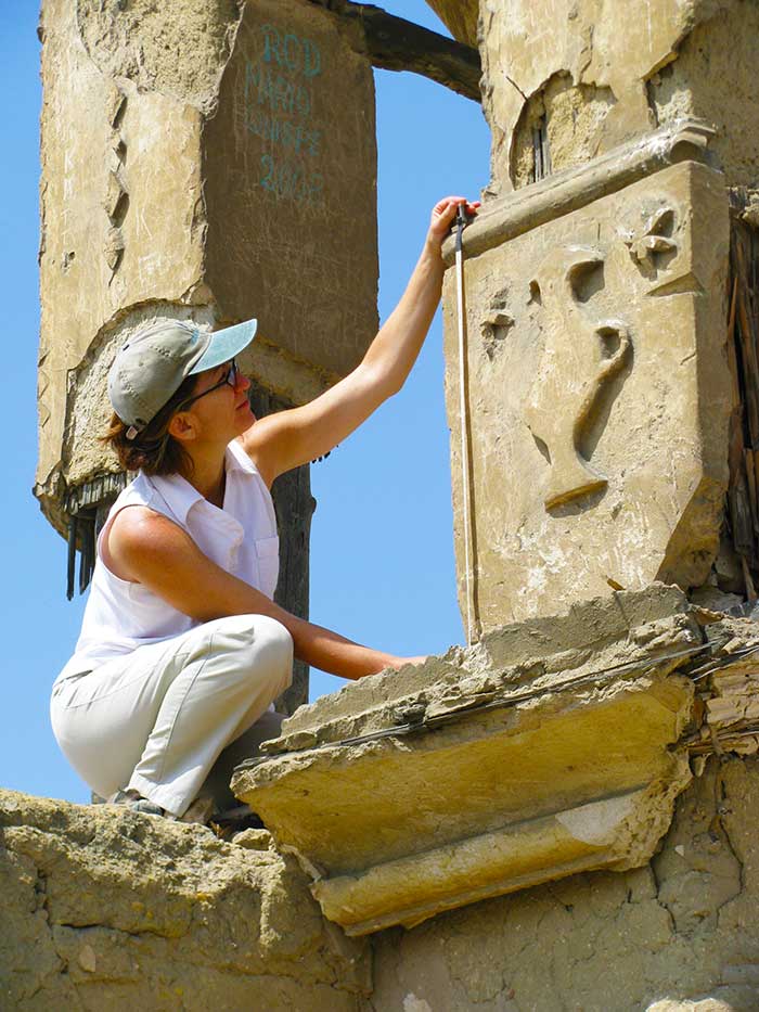 Lisa Leonardis sitting on a ledge of a stone building carved with images