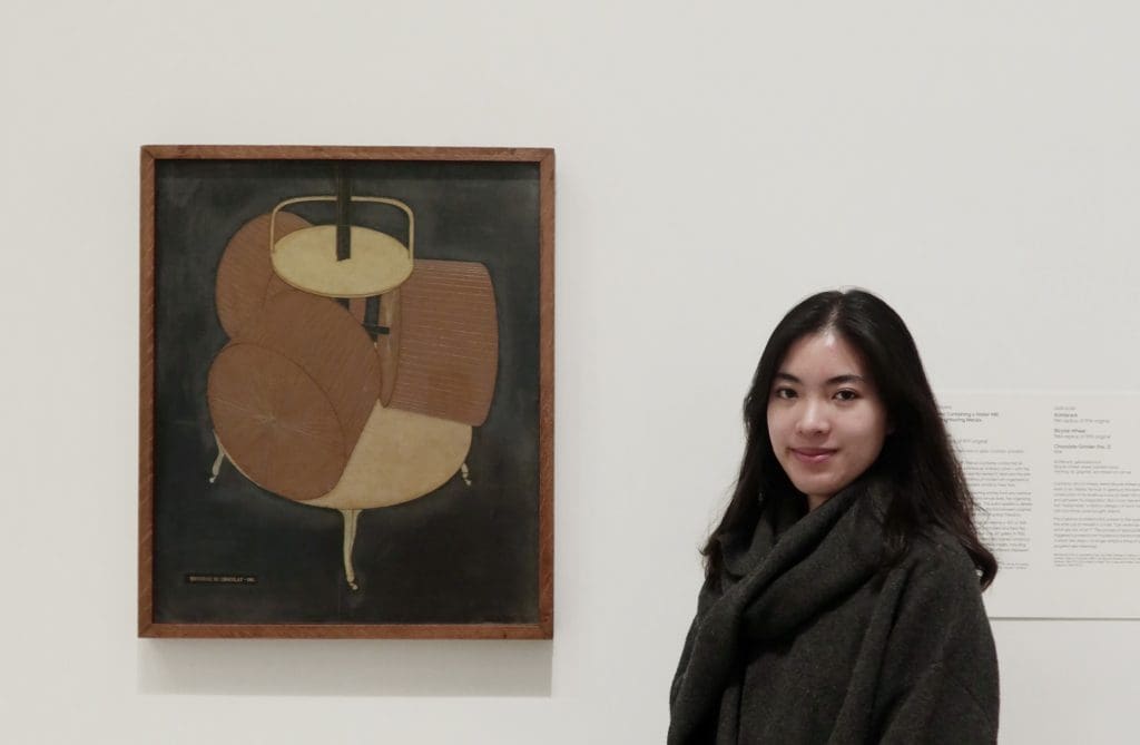 Woman standing next to a painting.