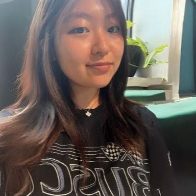 A soft smiling student with dark brown hair sitting in a cozy room with plants