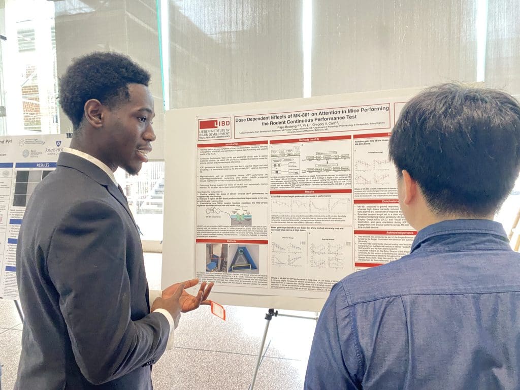 student presenting their poster to peer