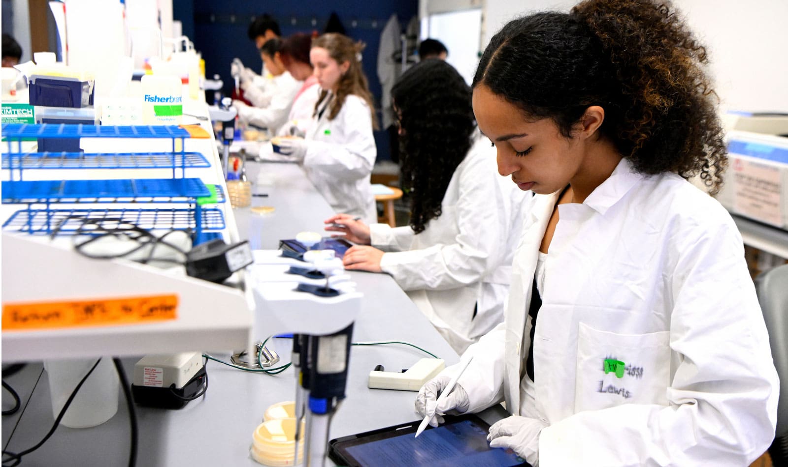 Undergraduate student working on a tablet in biology lab.