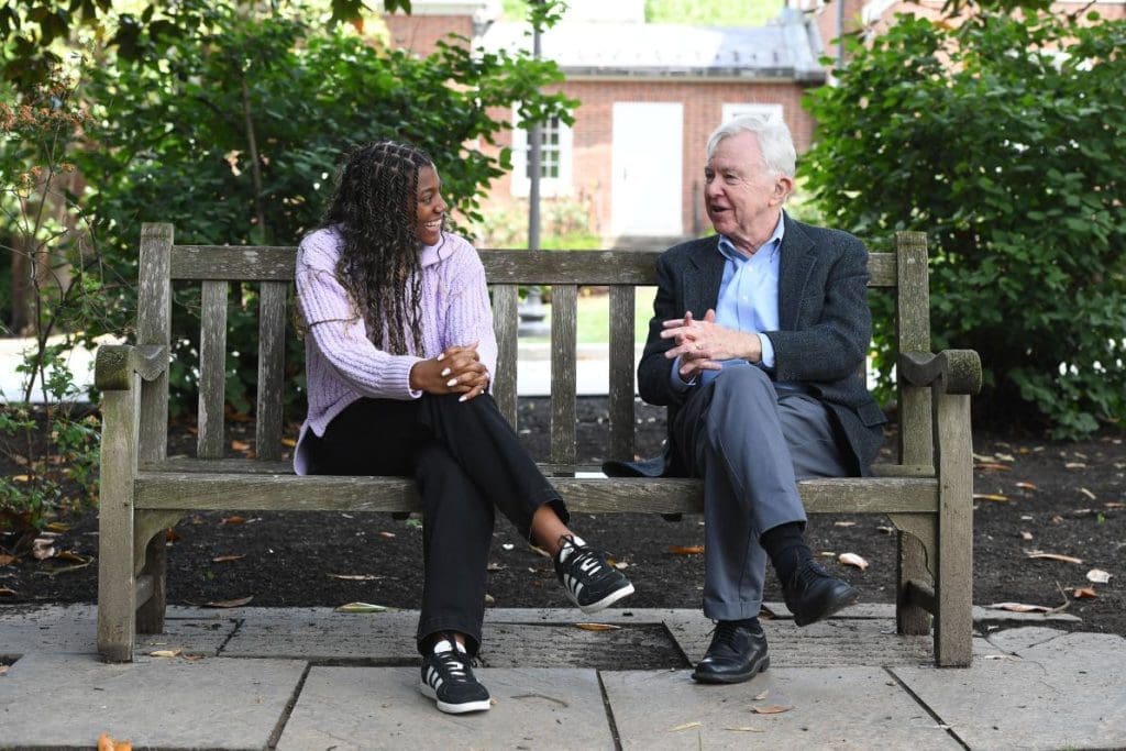 Arionna Bell and Robert Moffitt side by side on a wooden bench