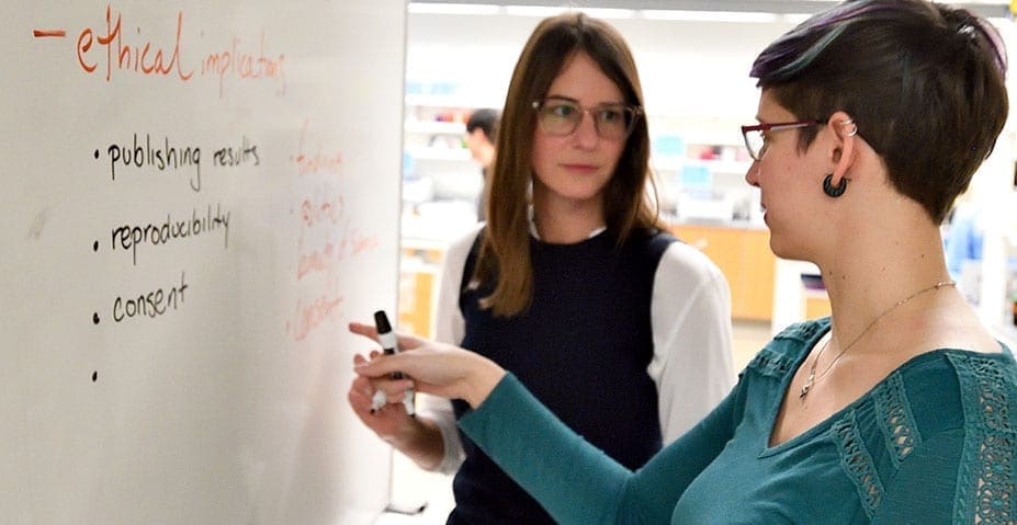 two women at whiteboard in discussion