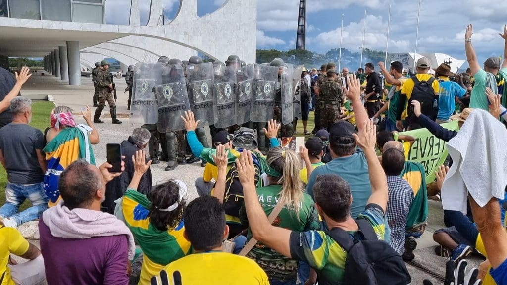 Riot police approaching a crowd clad in Brazilian flags