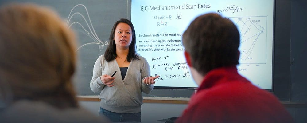 Chemistry professor Sarah Thoi in front of projection screen teaching undergraduate class, "Chemical Structure and Bonding".