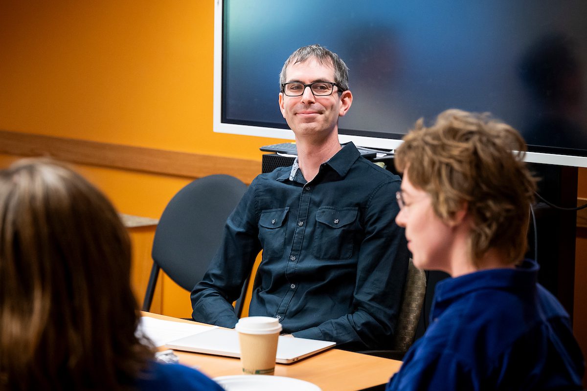 Stuart Schrader at a table listening to a student talking