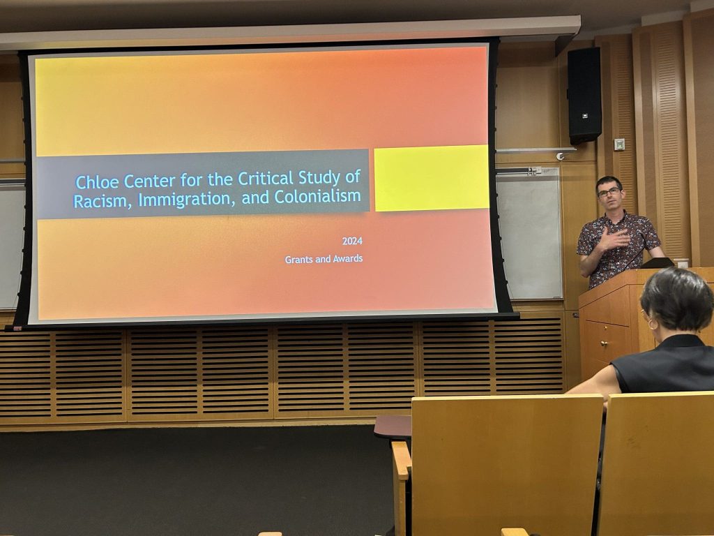 Stuart Schrader standing at a podium in front of a slide with the Chloe Center name