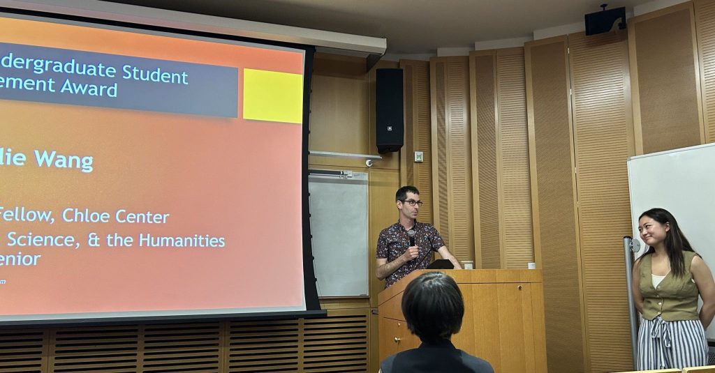 A man at a podium talking to a student grinning