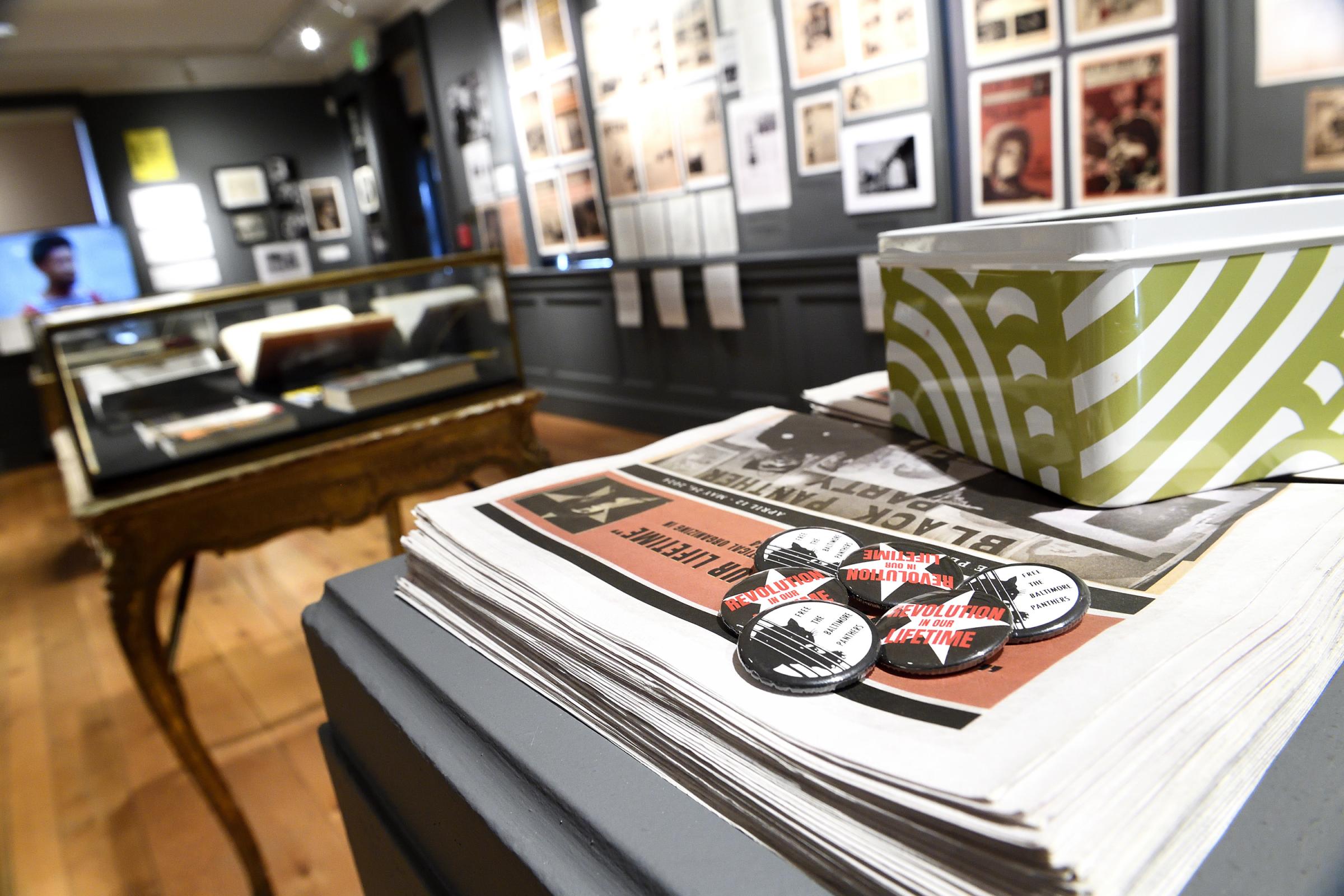 Black Panther newspapers with an exhibit showing posters in the background