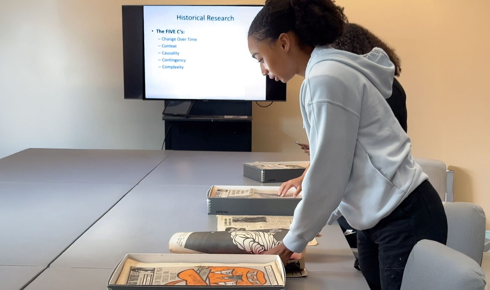 student looking at archival boxes filled with Black Panther newspaper editions