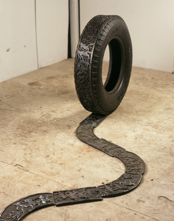 Sculpture of tire and tiles making a tire track, depicting a family crossing the border