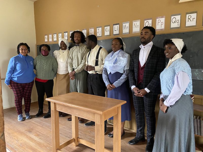 Students in period costume in schoolhouse