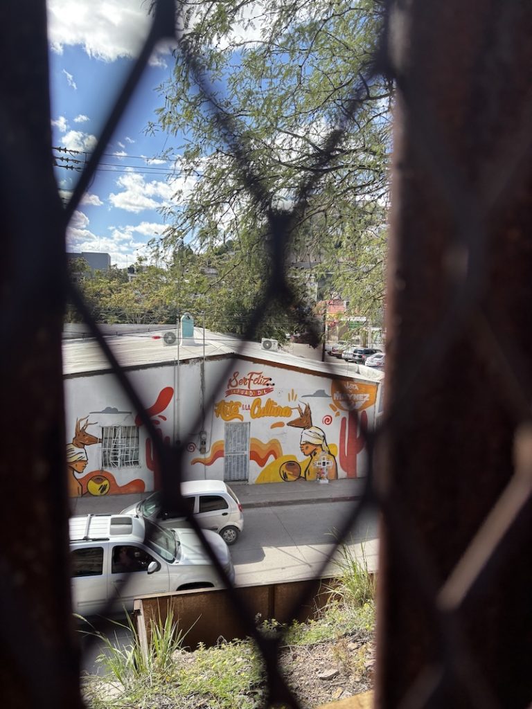 Photo of mural and memorial through border fence.