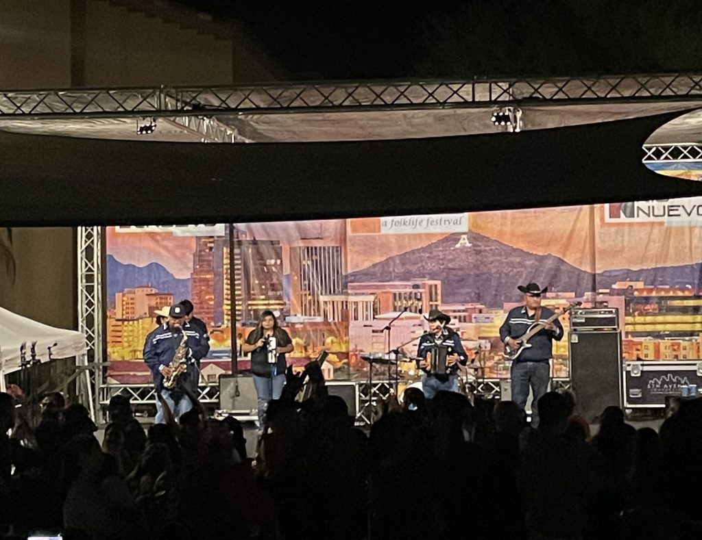 Band on stage in matching clothes with crowd dancing in front