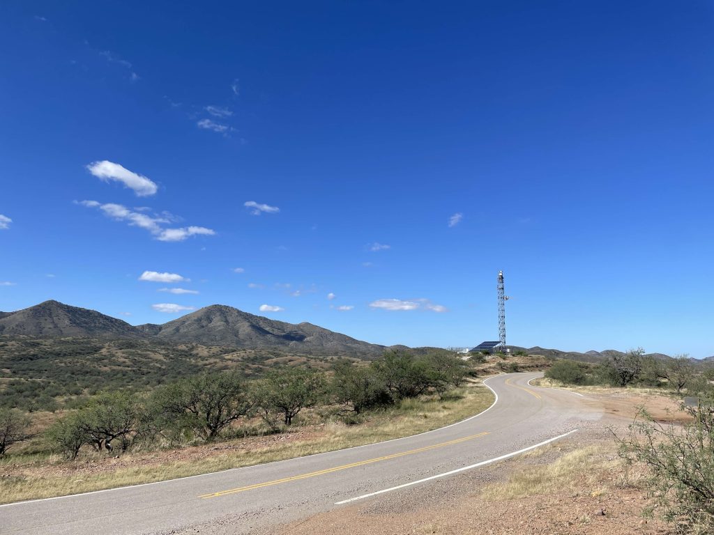 Tall surveillance tower in desert against blue sky