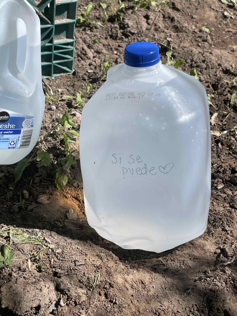 Water jug in desert with Si Se Puede written on it.