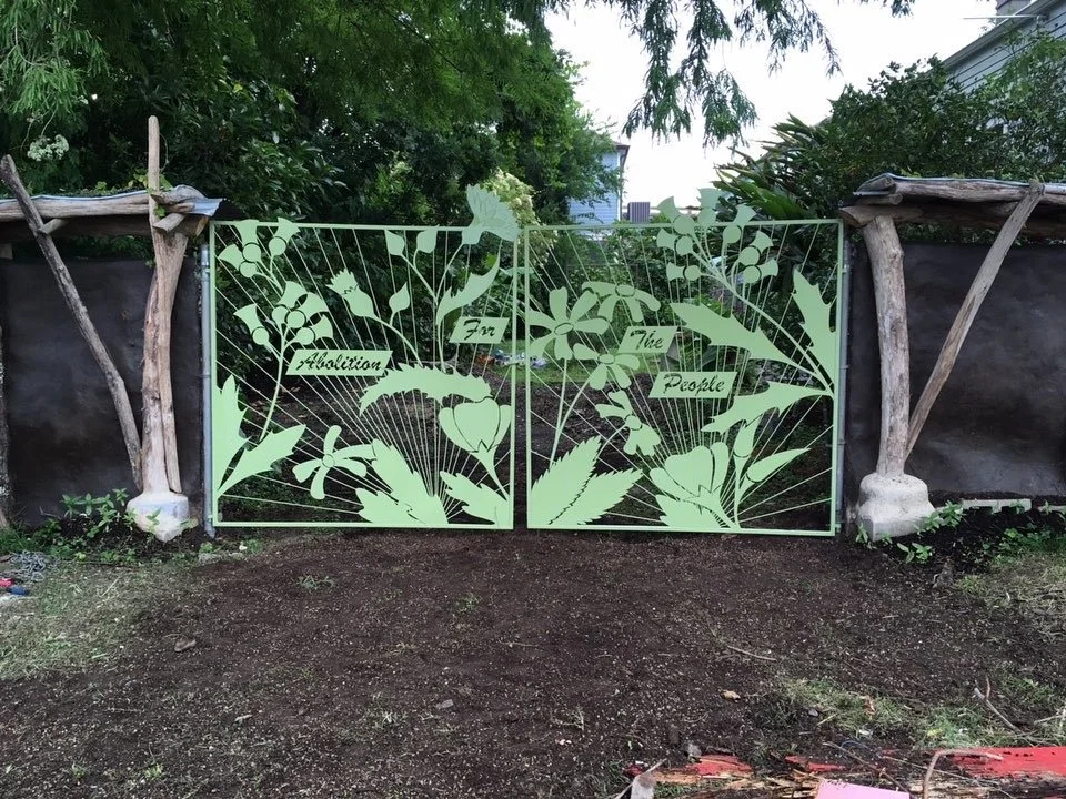 metal gate with green leaves and words spelling Abolition for the People