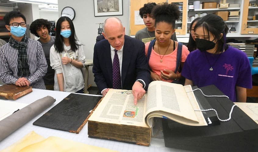 Dean Chris Celenza views a large, open book in special collections room as part of the "Books, Authenticity, and Truth" course.