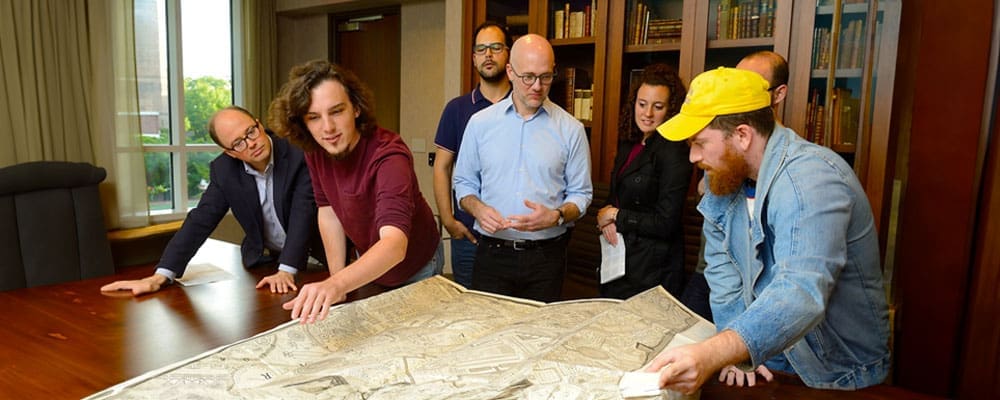 Classics professor Shane Butler (center), along with Earle Havens (far left), Curator of Rare Books and Manuscripts, led a session in JHU Library Special Collections for graduate students, exploring Piranesi's etchings.