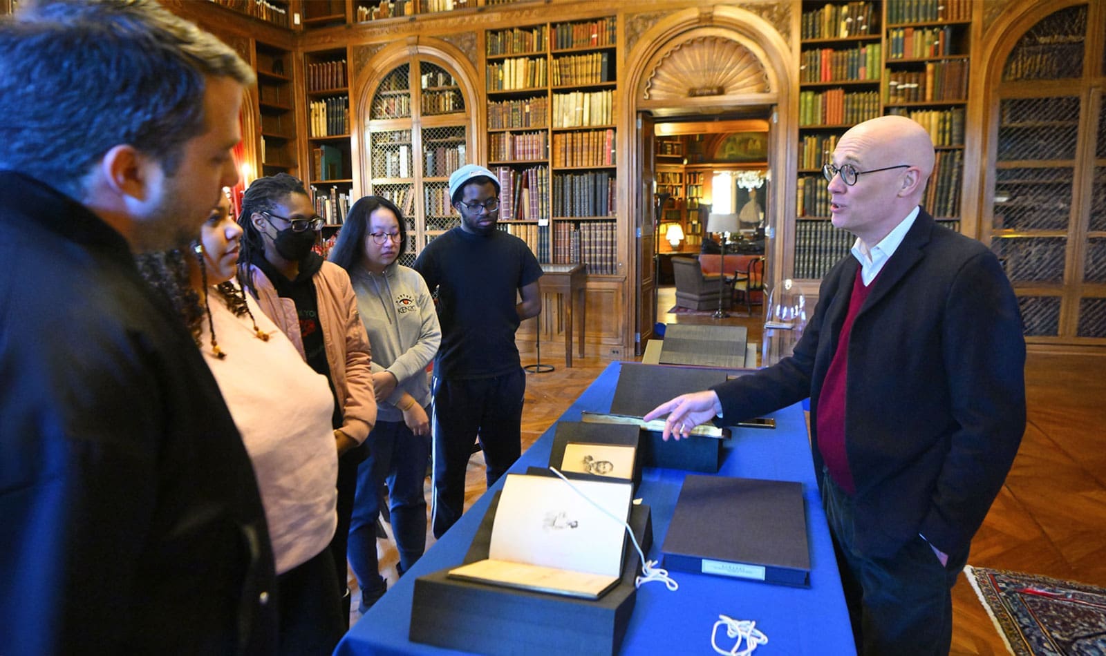 Faculty (Shane Butler) showing students rare books in Evergreen Library as part of Classics Research Lab class.