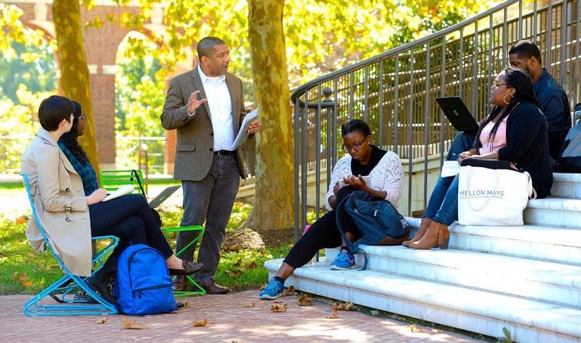On a sunny fall day, Professor Mark Christian Thompson teaches a small outdoor class on campus.