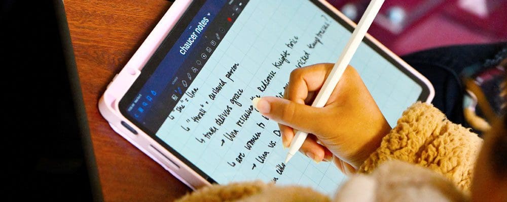 close-up of student's hand taking notes on iPad