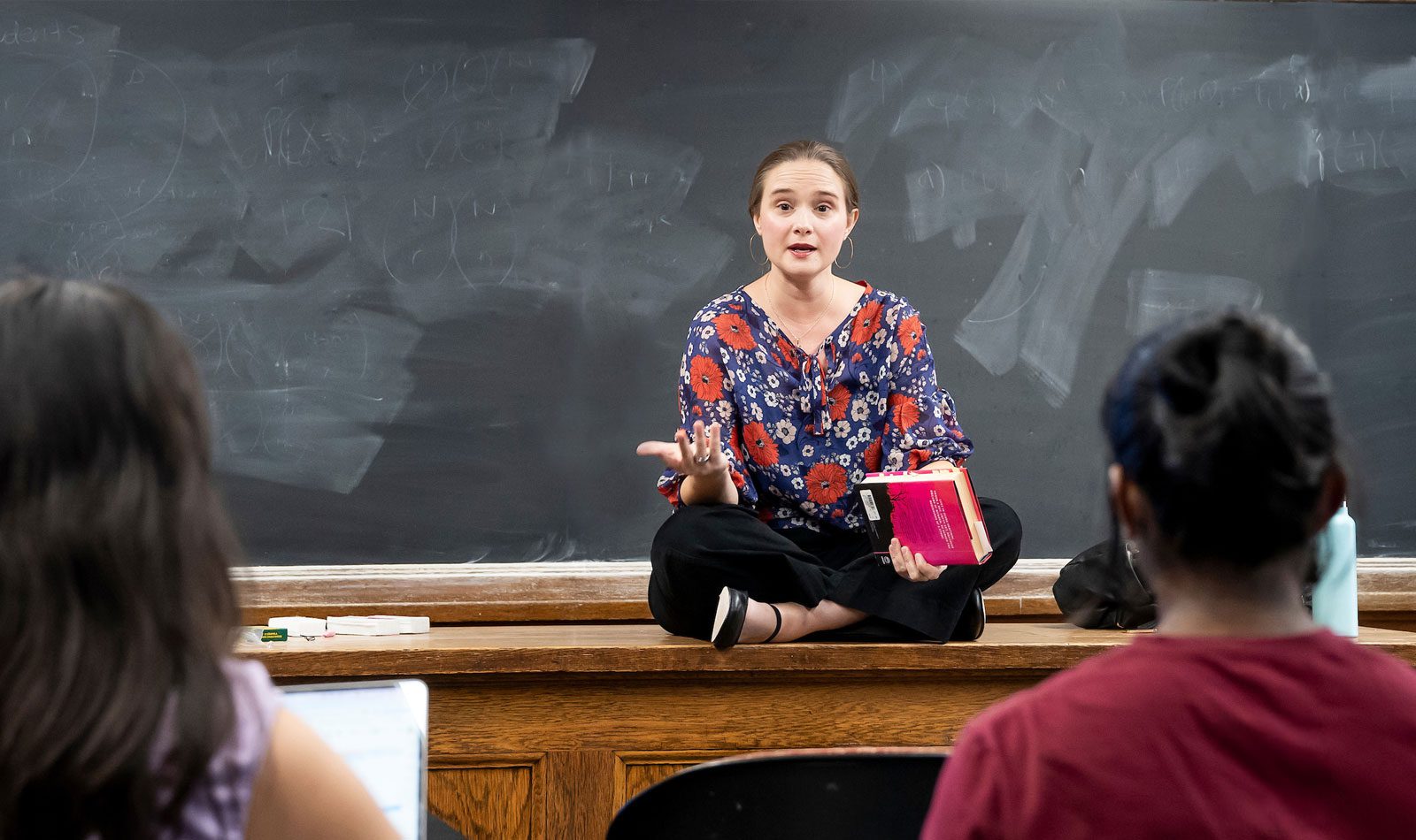 Faculty (Jeanne-Marie Jackson) sitting on top of a desk teaching English Class: Introduction to Literary Study.