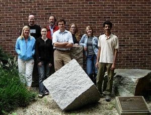 Group of people standing outside by a stone square