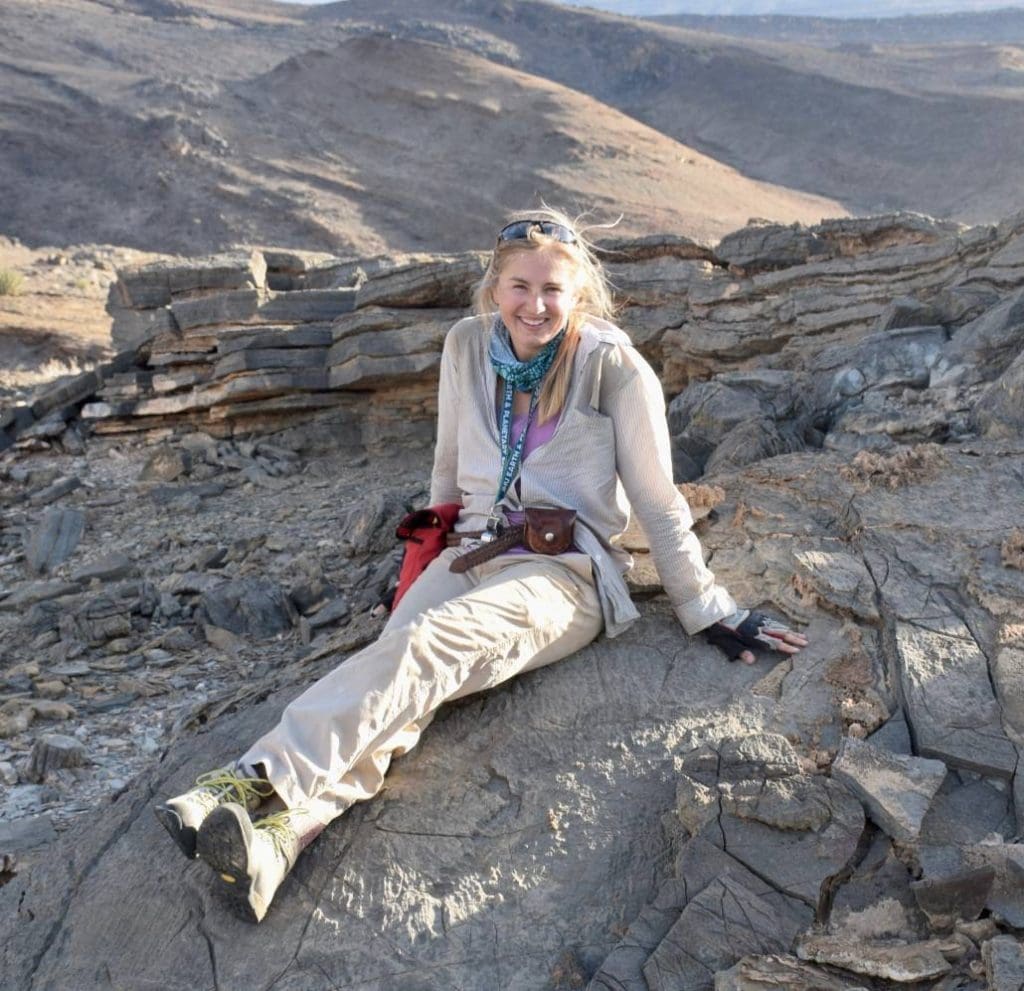 Emmy smith sitting on rocks in a desert-like area