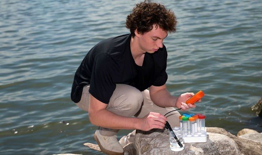Paul Gensbigler ’24 kneeling as he analyzes a water sample. His research is helping to answer unresolved questions about the kinds of bacteria removing nitrogen from the Chesapeake Bay.