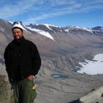 Person standing on a mountain with a snowy lake in the distance