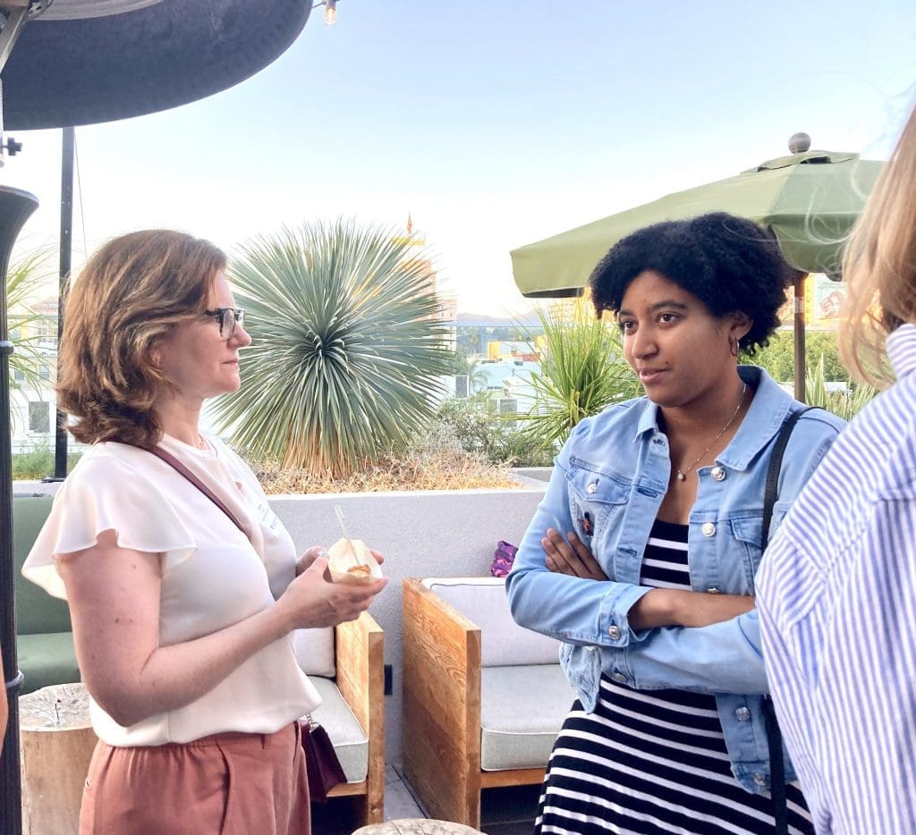 Vice Dean Erin Rowe talking with a student on a rooftop porch with palm trees