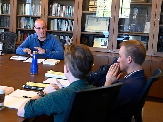 angus burgin at a conference table with two graduate students