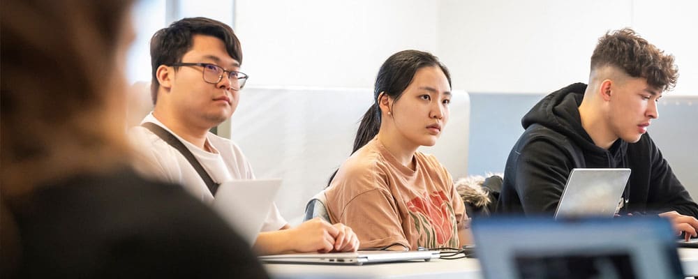 Three undergraduate students listening in class.