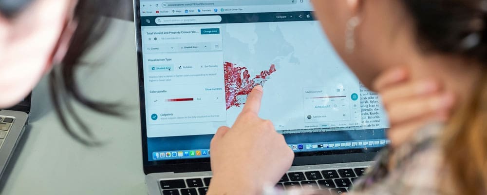 Closeup of two students looking at a map on a computer screen.