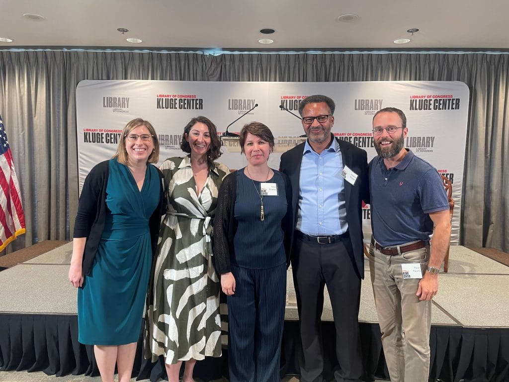 FIve JHU affiliates standing in front of a stage