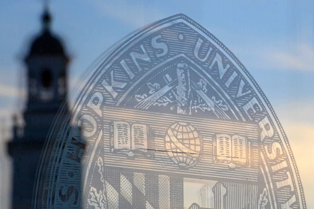 Johns Hopkins seal on glass with tower in the background