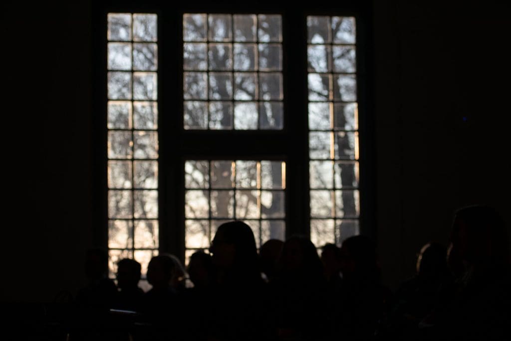 Golden hour sunlight streaming into Levering Hall, reflecting off silhouetted attendees during an AGHI event.