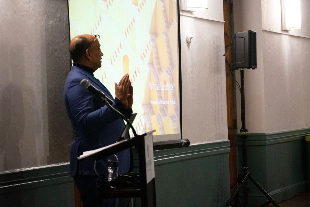 Kwame Anthony Appiah speaking at podium with slide presentation behind him.