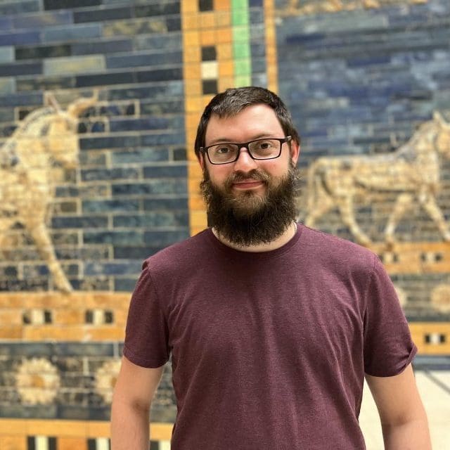 Michael Chapin (bearded young man) stands in front of an ancient mosaic.