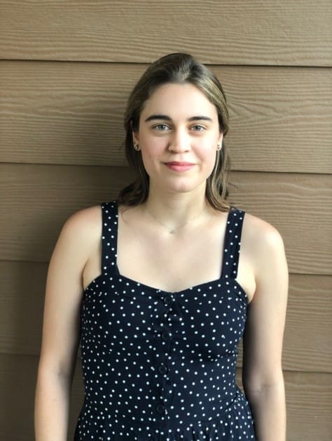 Eleni wearing polka dot dress in front of a wooden wall 