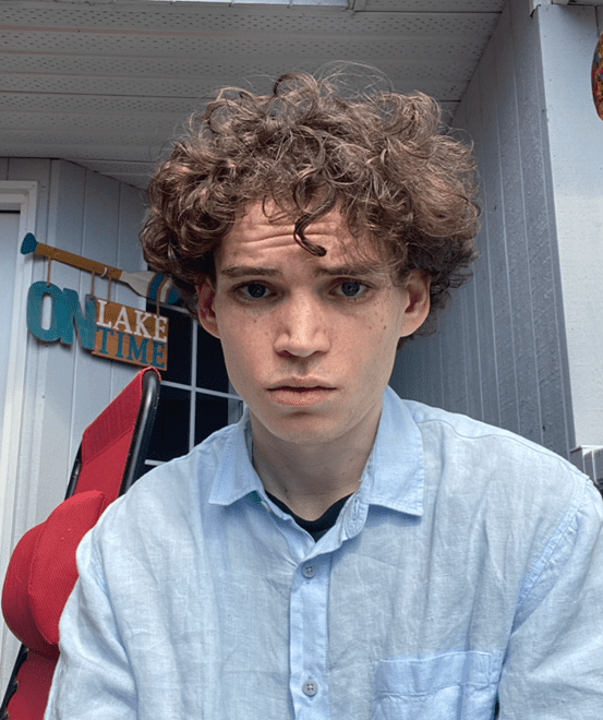 Jonah wearing a light blue button up shirt with short curly hair