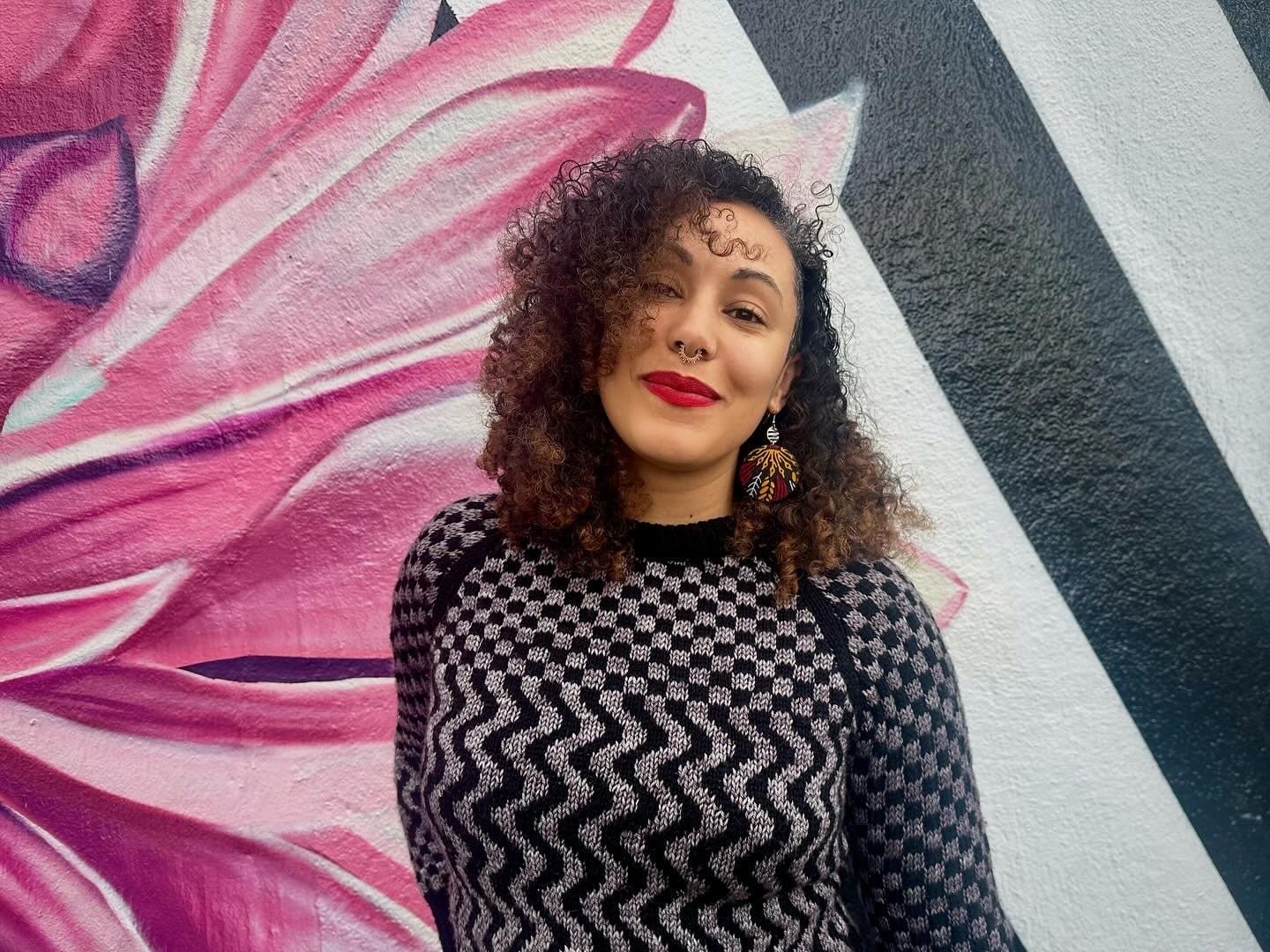 Camilla Hawthorne in front of a mural of a pink flower