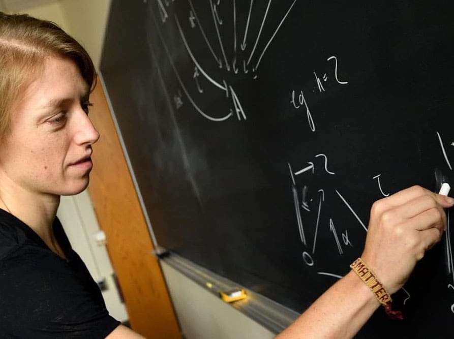 professor Emily Riehl completing a problem on the blackboard