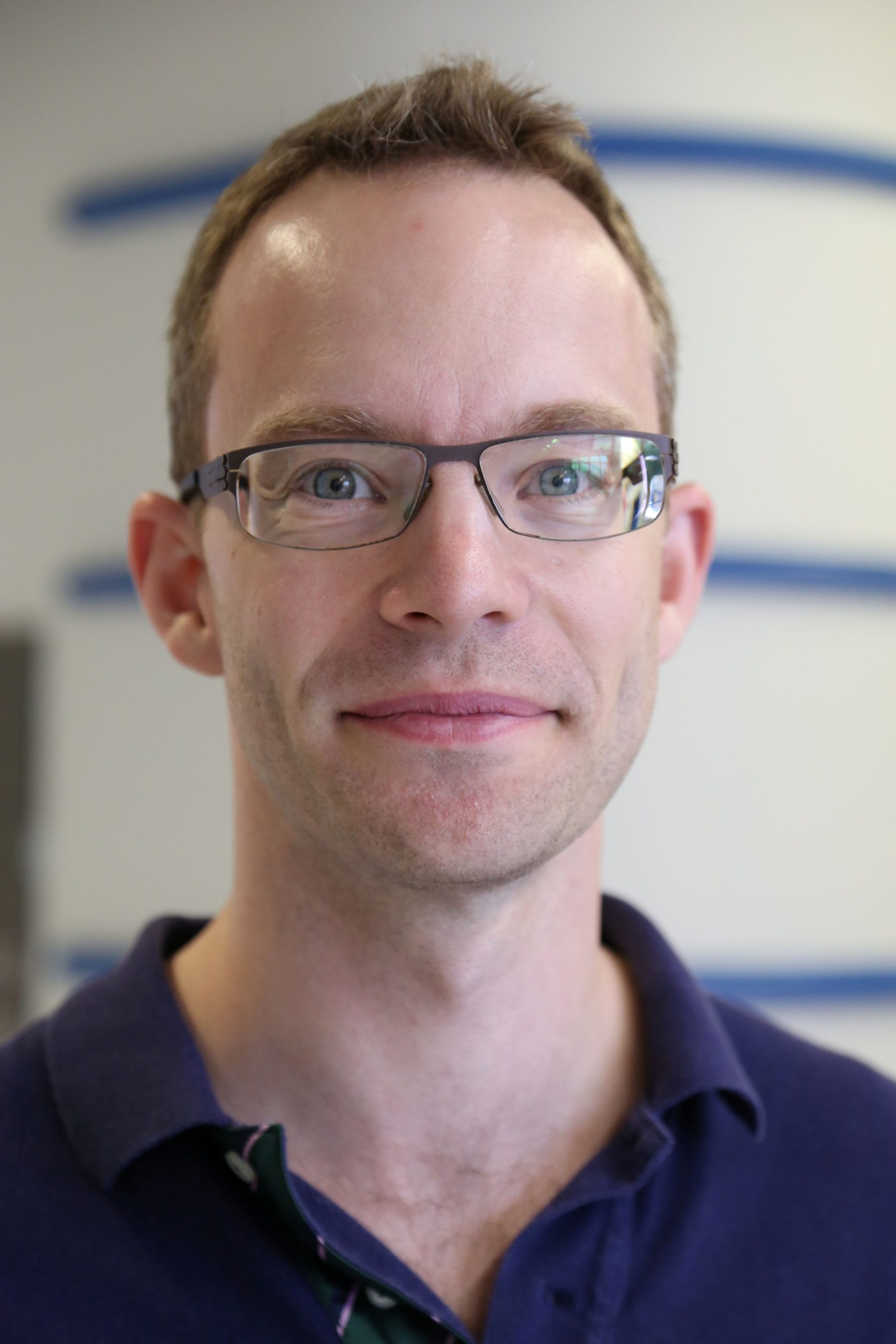 image of clean shaved man with glasses and a blue shirt