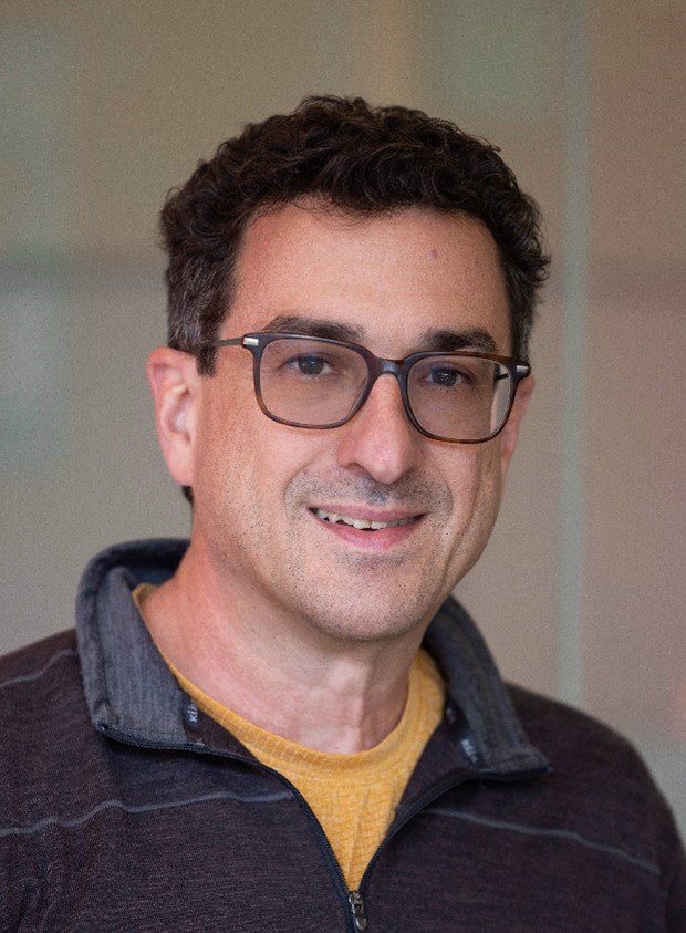 Dr. Greg DeAngelis in a smiling photo with glasses and casual attire