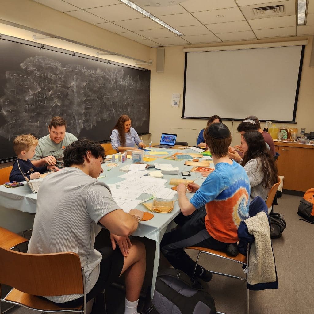 10 students around a large table working on crafts with paper