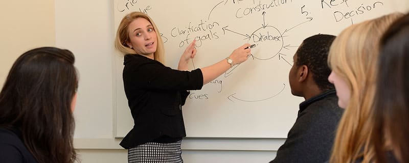 Prof. Papadakis at a whiteboard explaining theories to several students