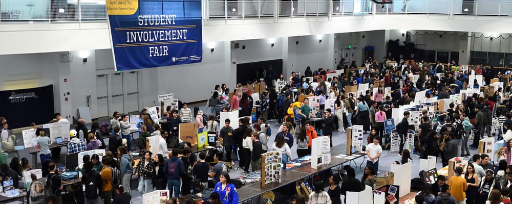2024 Student Involvement Fair - an overhead view of gym full of students looking at table displays of various student group opportunities.